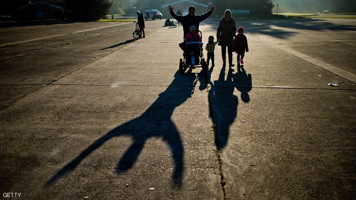Members of a refugee family from Syria cast long shadows as they walk over the grounds of former military barracks serving now as shelter for asylum seekers on November 3, 2015 in Ehra-Lessien near Wolfsburg, central Germany, on November 3, 2015.         AFP PHOTO / DPA / JULIAN STRATENSCHULTE   +++   GERMANY OUT   +++        (Photo credit should read JULIAN STRATENSCHULTE/AFP/Getty Images)