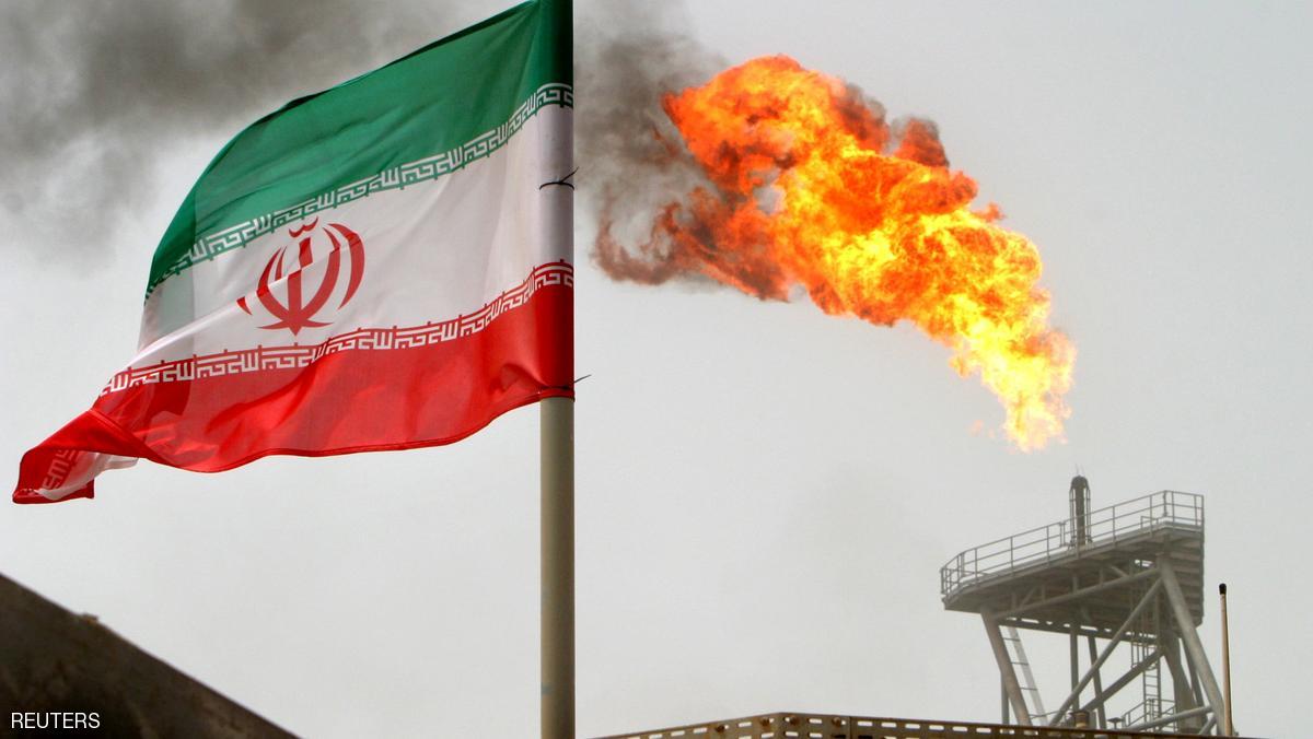 A gas flare on an oil production platform is seen alongside an Iranian flag in the Gulf