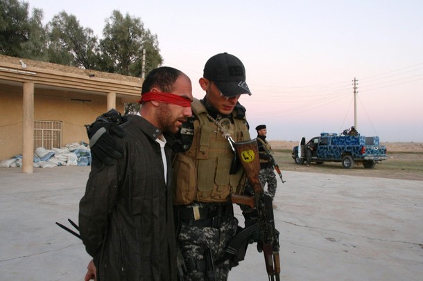 An Iraqi policeman escorts a suspected insurgent after a raid at an area south of Tikrit, some 150 km (95 miles) north of Baghdad November 6, 2010. Police forces arrested seven suspected militants and confiscated an ammunition cache, a police official said on Saturday. REUTERS/Sabah al-Bazee (IRAQ - Tags: CONFLICT MILITARY)